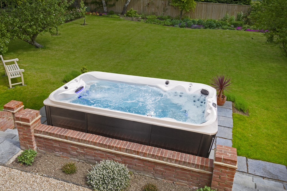 swim spa in backyard with a view of green grass