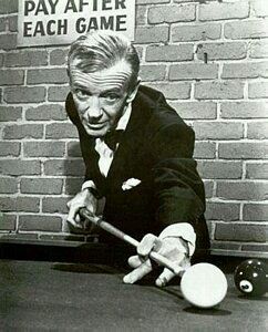 man in a suit playing billiard